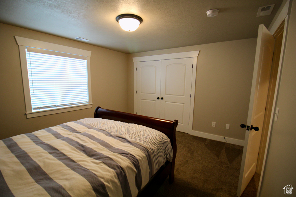 Bedroom featuring dark colored carpet and a closet