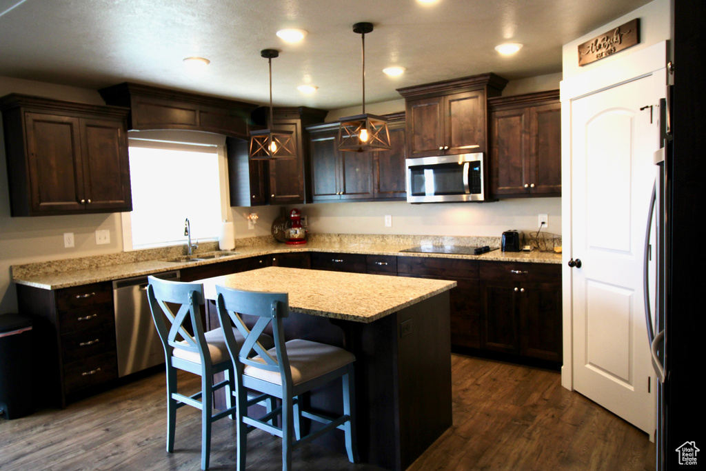 Kitchen with a center island, sink, dark hardwood / wood-style floors, and stainless steel appliances