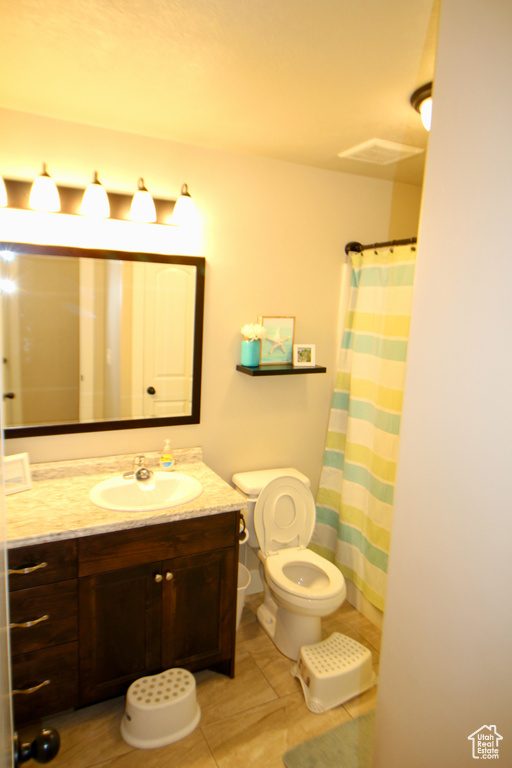 Bathroom featuring vanity, tile patterned flooring, and toilet