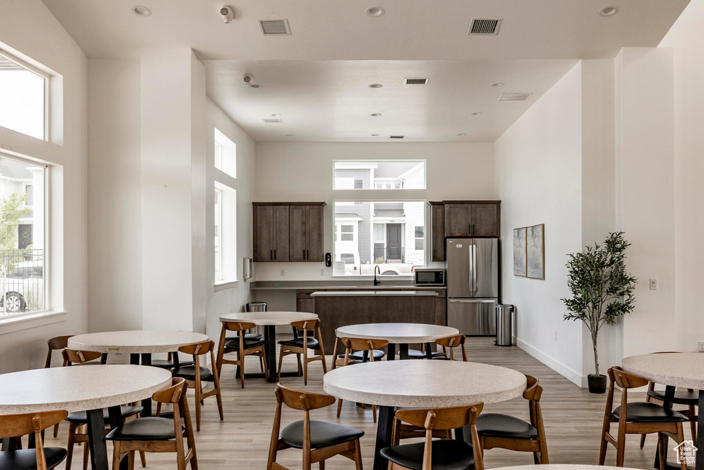 Dining space with sink, light wood-type flooring, and a high ceiling