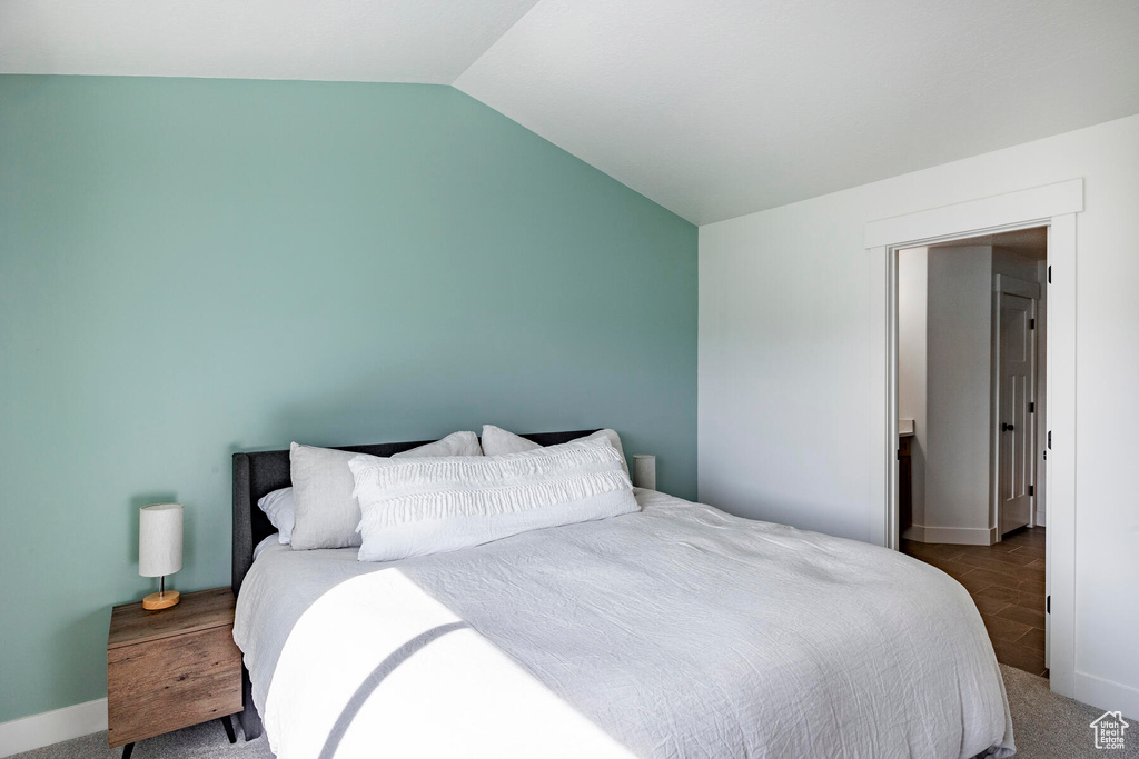 Bedroom with lofted ceiling and dark colored carpet