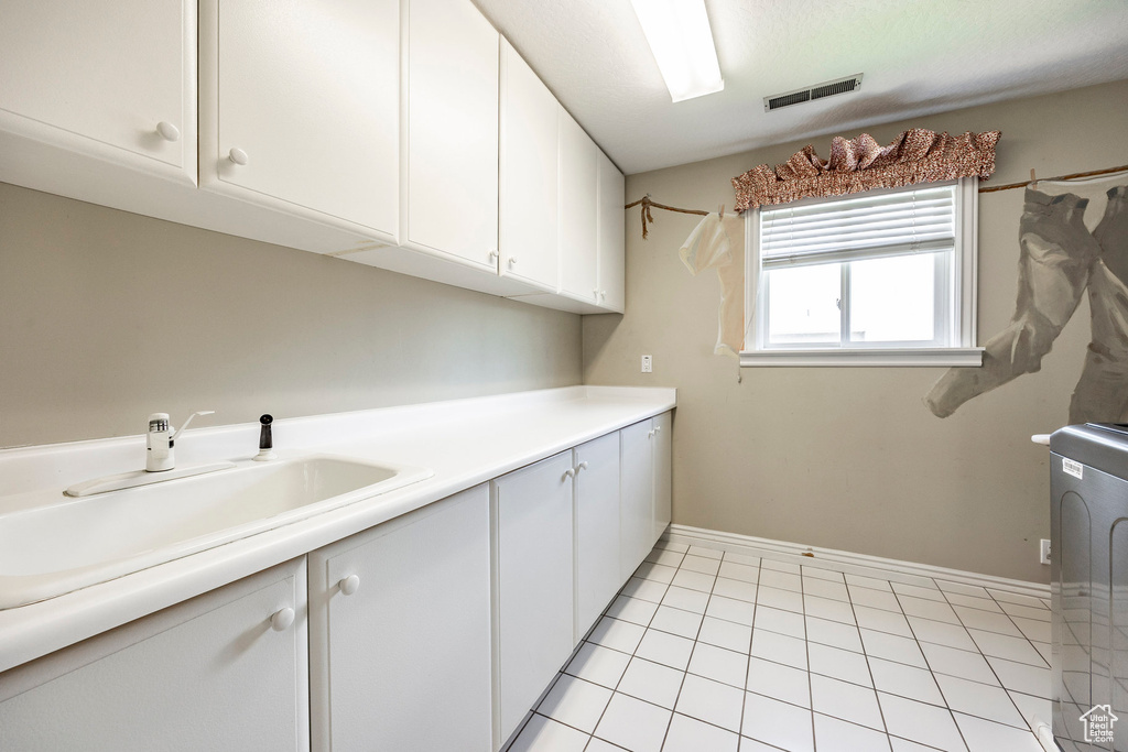 Laundry area featuring sink, washer / clothes dryer, cabinets, and light tile patterned floors