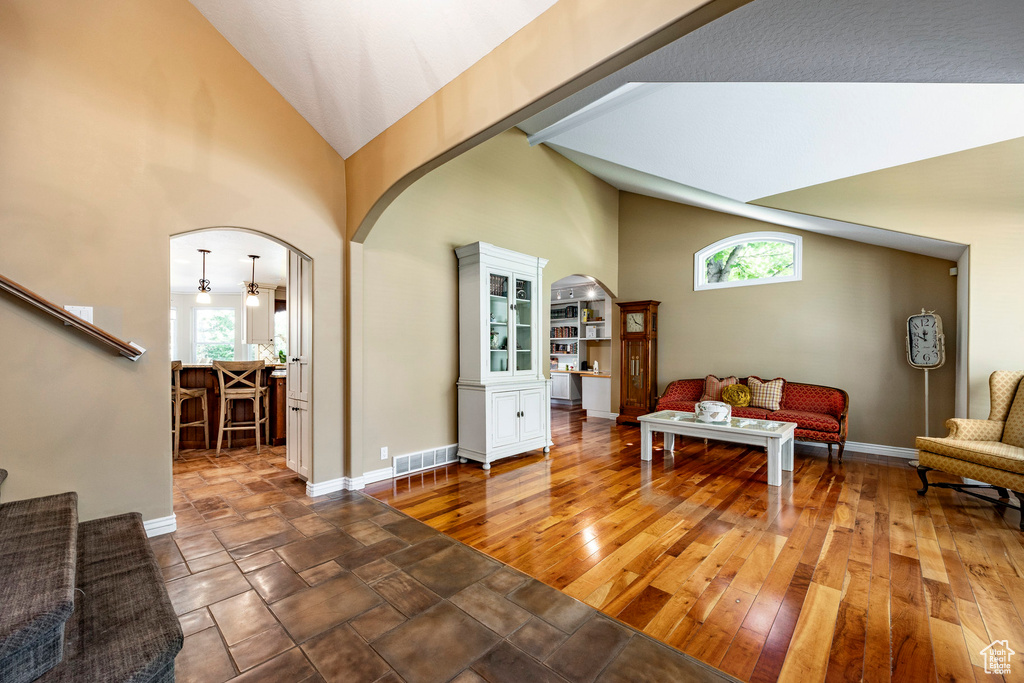 Living area with a wealth of natural light, high vaulted ceiling, and hardwood / wood-style floors