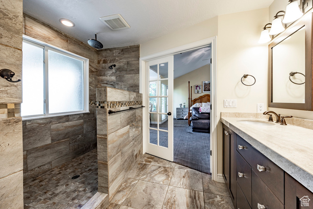 Bathroom featuring tile patterned floors, french doors, vanity, and tiled shower