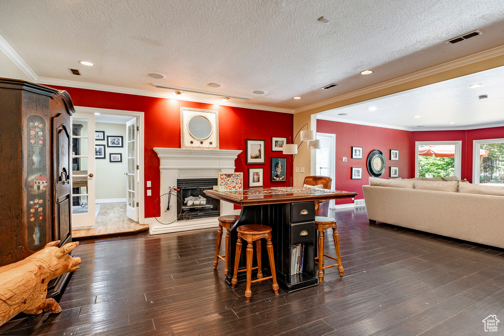 Dining space featuring dark hardwood / wood-style flooring, a textured ceiling, and ornamental molding