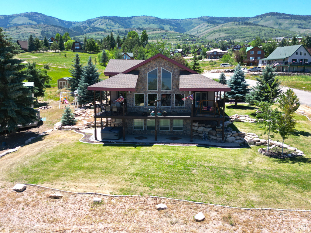 Rear view of house featuring a patio, a deck with mountain view, and a yard