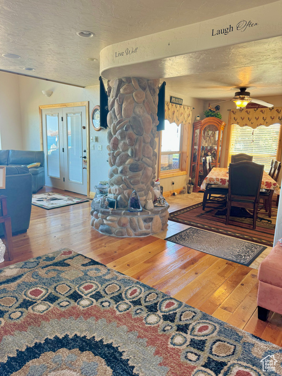 Living room with a textured ceiling, ceiling fan, and hardwood / wood-style floors