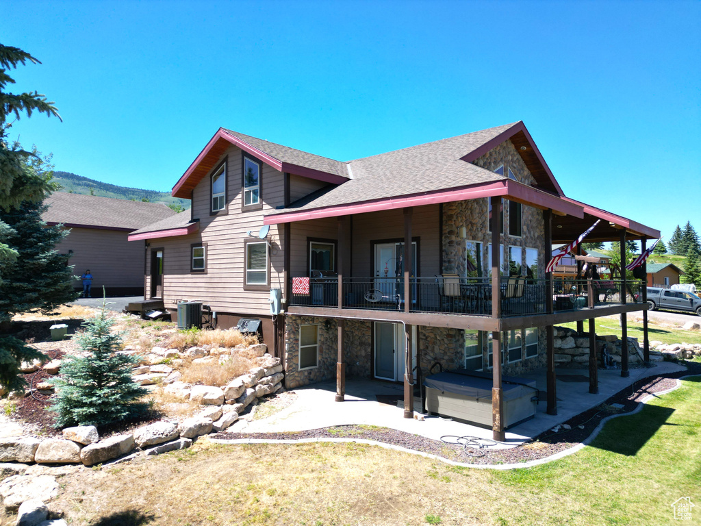 Back of property featuring a patio, a balcony, a lawn, and central air condition unit