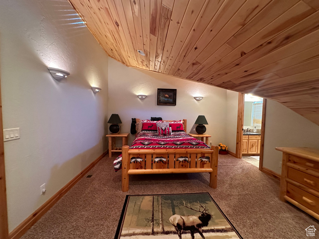 Carpeted bedroom with ensuite bathroom, wooden ceiling, and vaulted ceiling