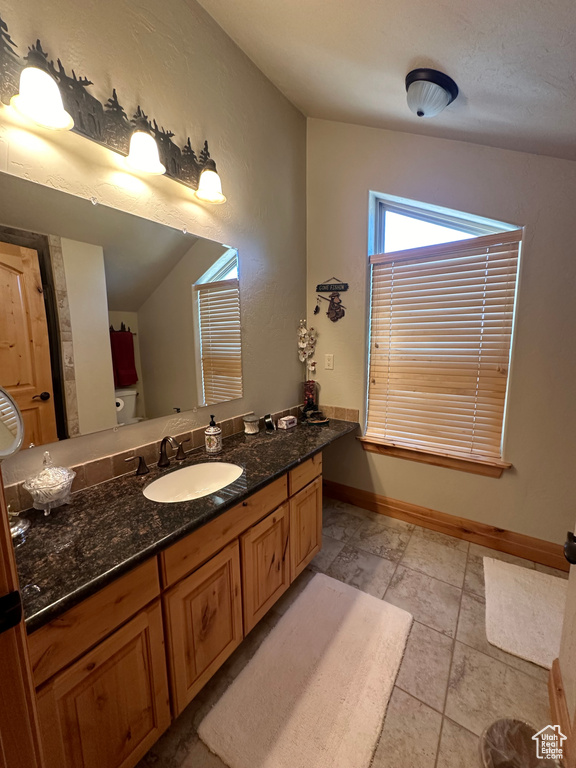 Bathroom with lofted ceiling, tile patterned floors, and vanity