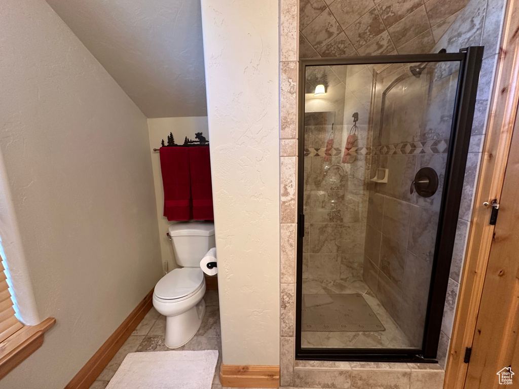 Bathroom featuring a shower with shower door, toilet, and tile patterned floors