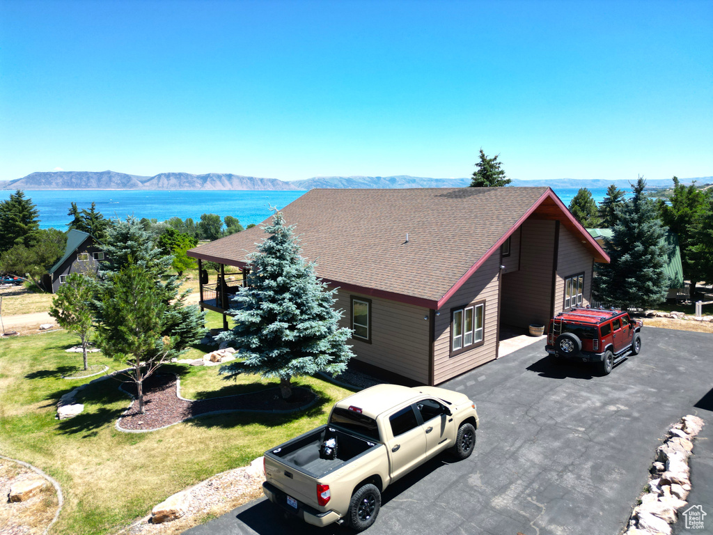 View of front of property with a water and mountain view and a front lawn