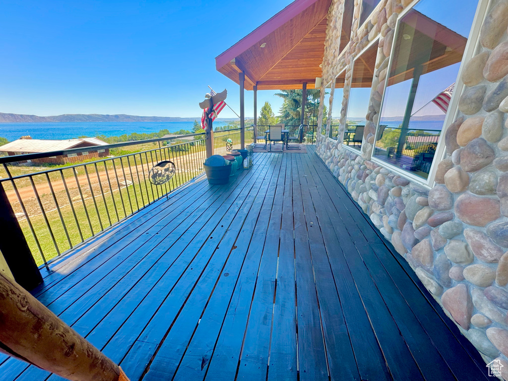 Wooden deck featuring a water view and a lawn