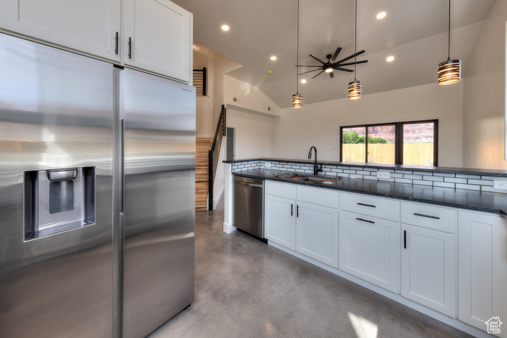 Kitchen with sink, decorative backsplash, hanging light fixtures, appliances with stainless steel finishes, and white cabinets