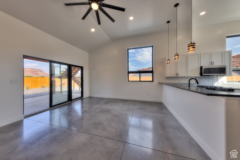 Unfurnished living room featuring high vaulted ceiling, a healthy amount of sunlight, and ceiling fan