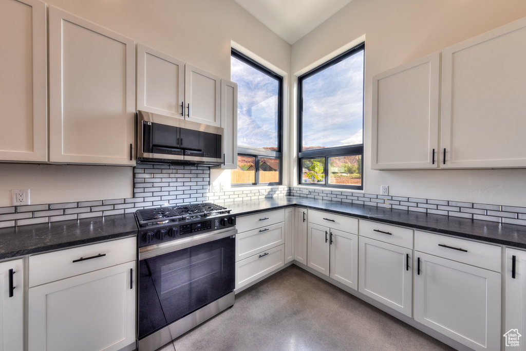 Kitchen with appliances with stainless steel finishes, white cabinetry, and dark stone counters