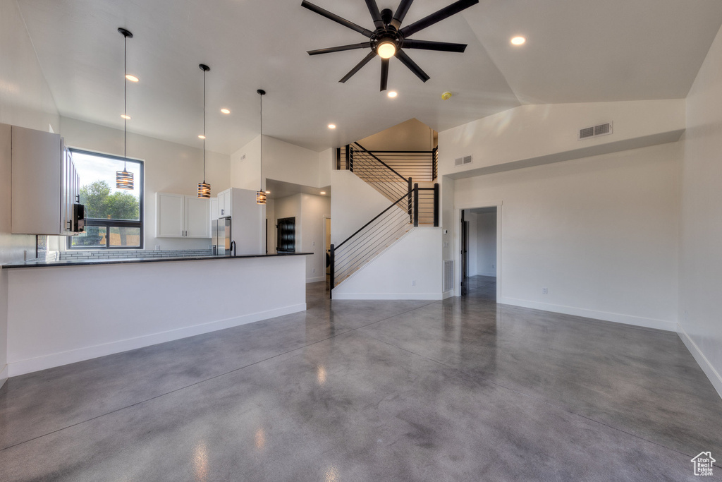 Unfurnished living room featuring ceiling fan, high vaulted ceiling, and concrete flooring