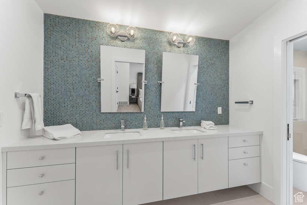 Bathroom with tile patterned flooring, toilet, and dual bowl vanity