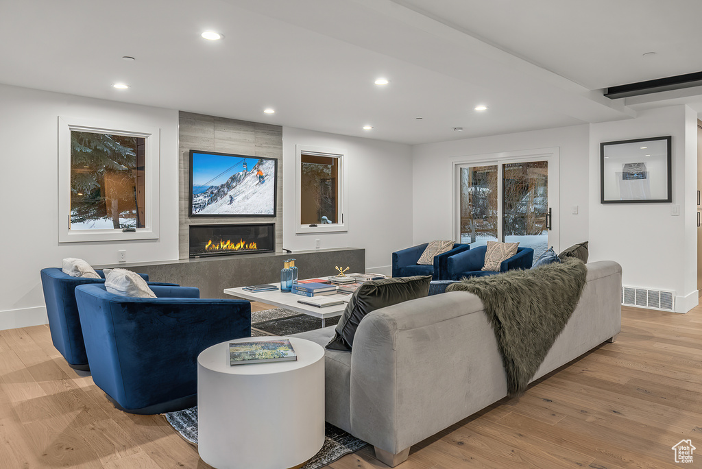 Living room with light hardwood / wood-style flooring and a tiled fireplace