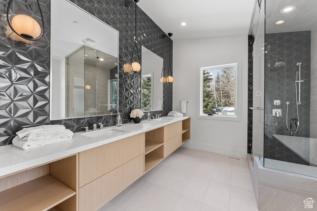 Bathroom with a shower with shower door, lofted ceiling, double sink vanity, and tile patterned flooring