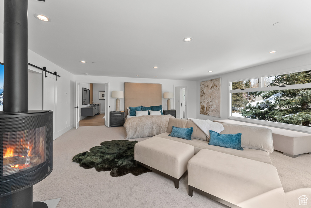 Living room with a wood stove, a barn door, and light colored carpet