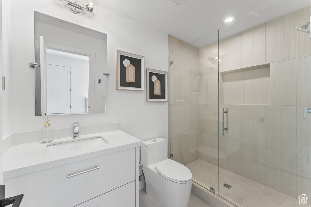 Bathroom featuring a shower with shower door, vanity, and toilet