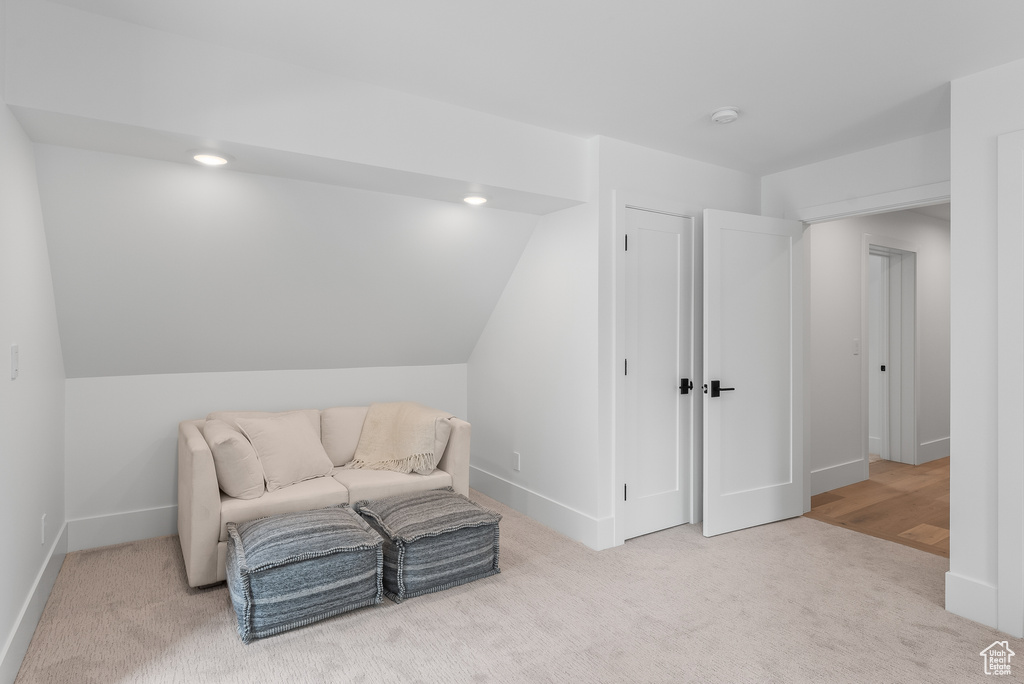 Sitting room with lofted ceiling and light colored carpet