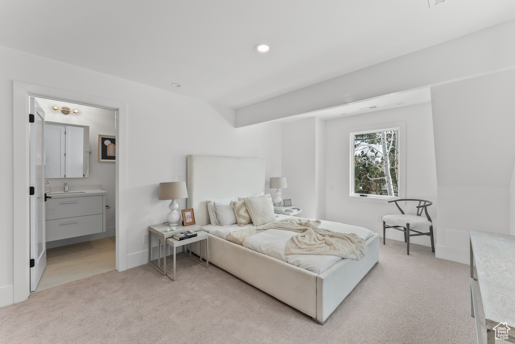 Carpeted bedroom featuring ensuite bathroom and sink