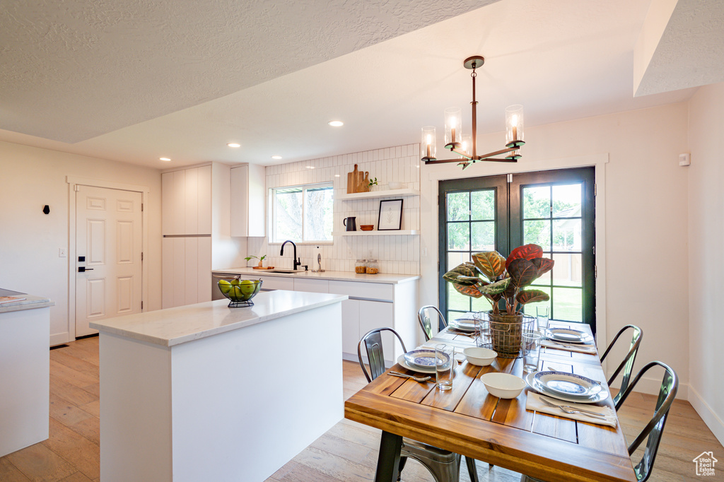 Kitchen featuring decorative light fixtures, white cabinetry, plenty of natural light, and backsplash