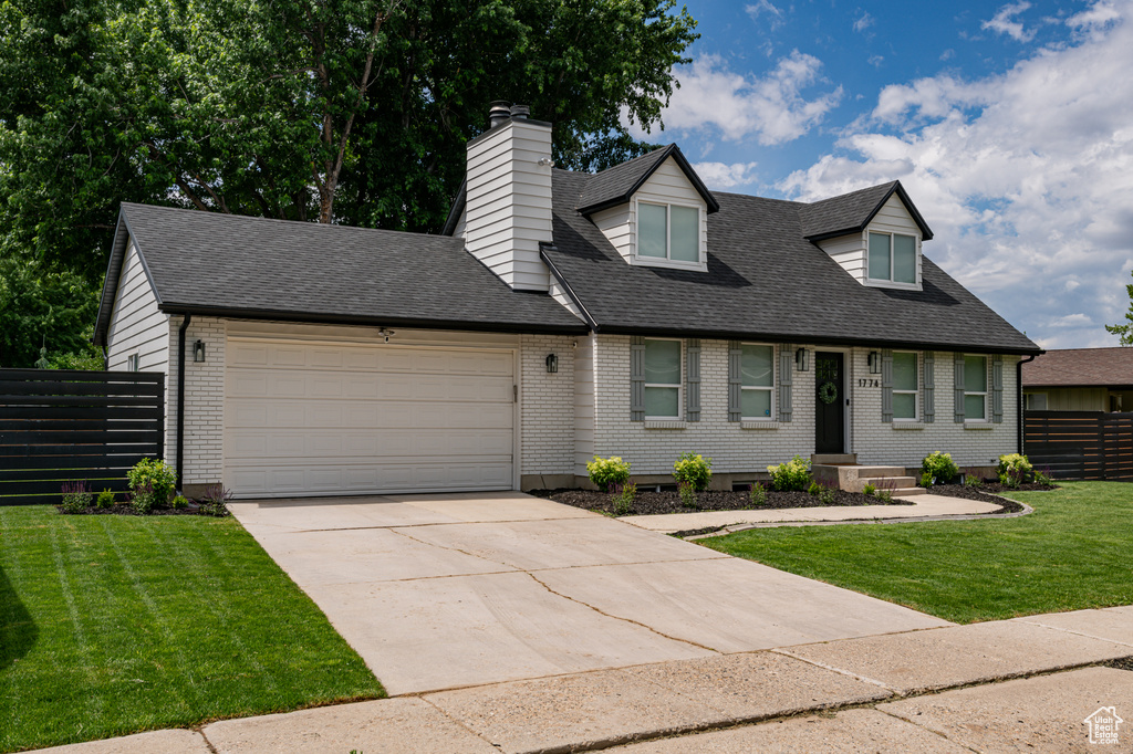 New england style home featuring a garage and a front lawn