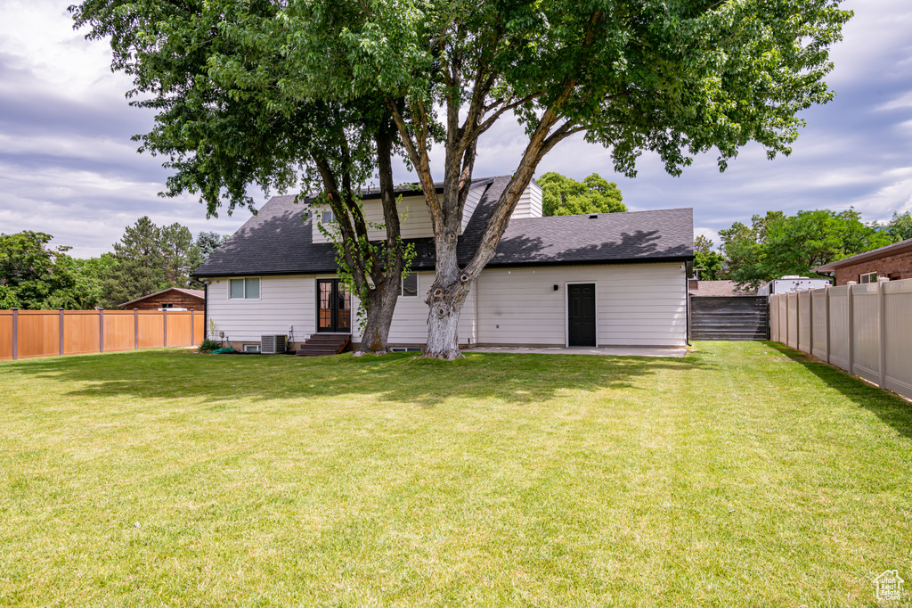 Back of property with a yard and central AC