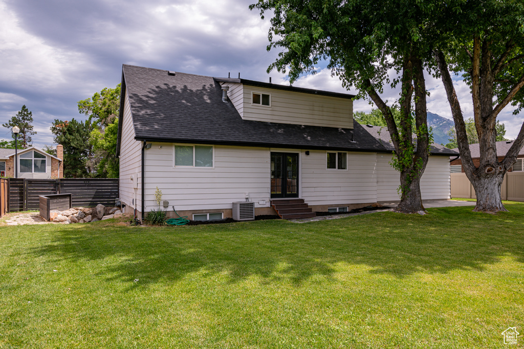 Rear view of property with central AC unit and a yard