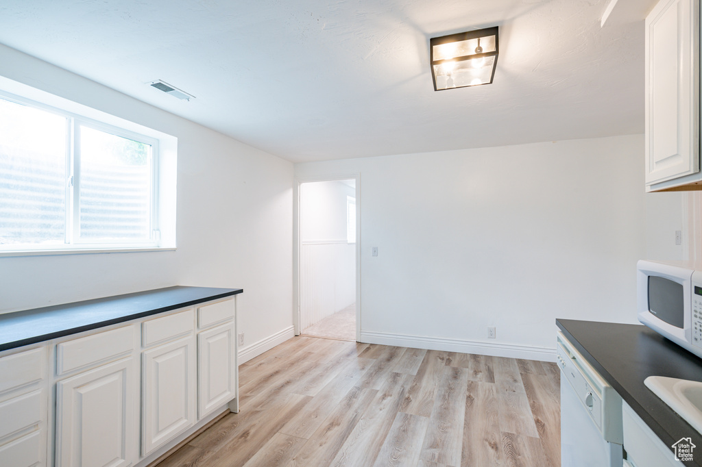 Kitchen featuring white cabinets, light hardwood / wood-style floors, white appliances, and sink