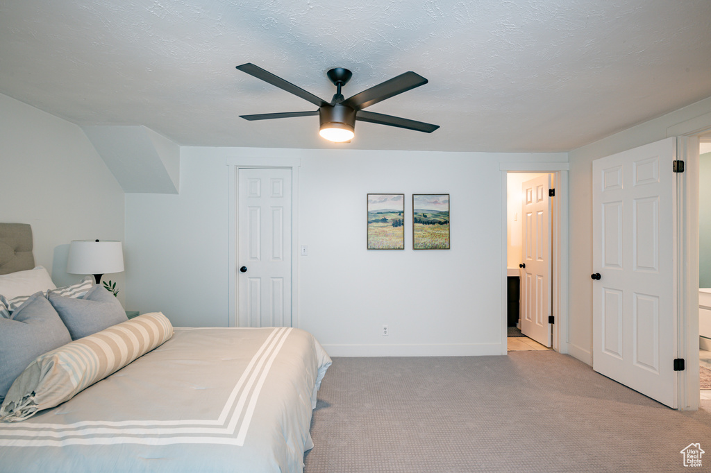 Carpeted bedroom featuring ensuite bathroom and ceiling fan