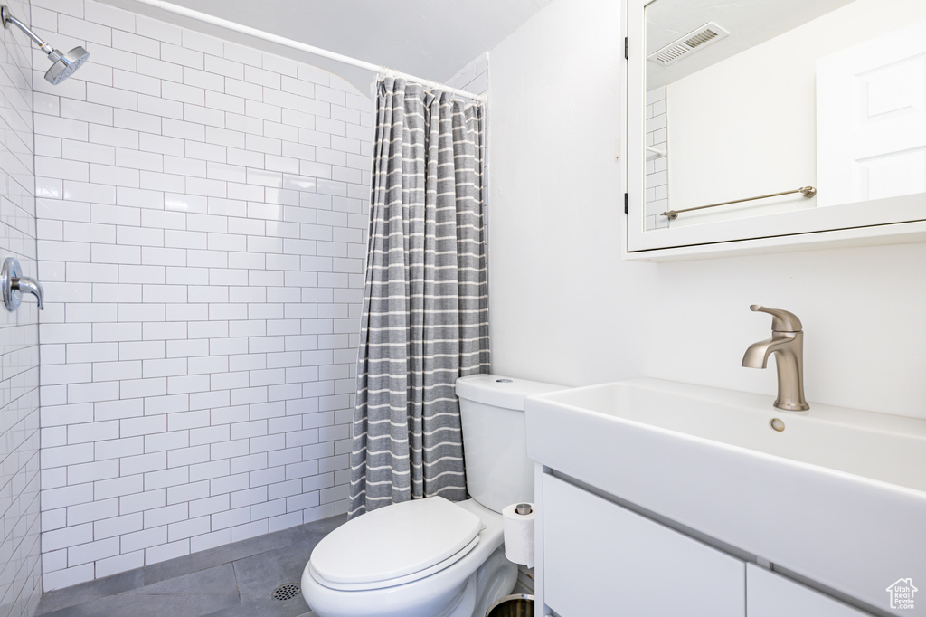 Bathroom featuring tile patterned flooring, a shower with curtain, toilet, and vanity