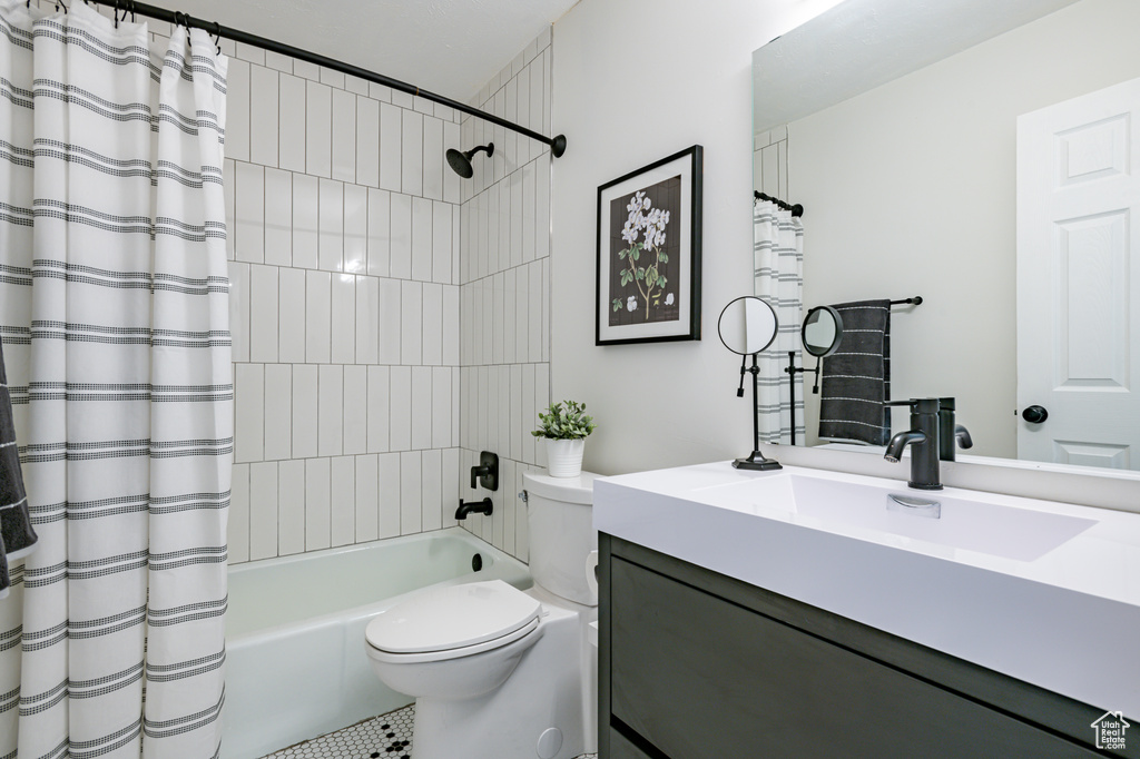 Full bathroom with vanity, tile patterned floors, toilet, and shower / bath combination with curtain