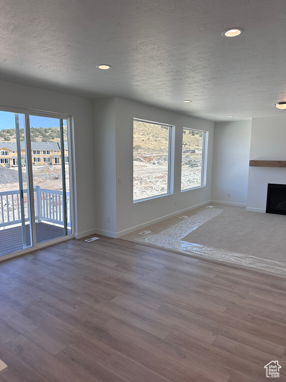 Unfurnished living room with a textured ceiling and hardwood / wood-style floors