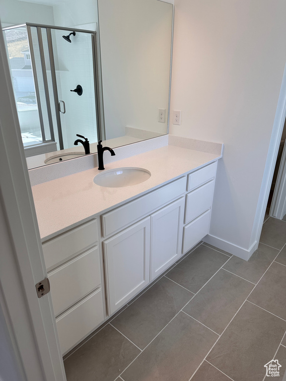 Bathroom featuring walk in shower, vanity, and tile patterned floors