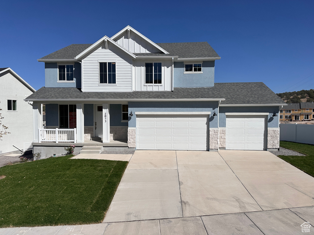 View of front of house with a front yard, a garage, and a porch