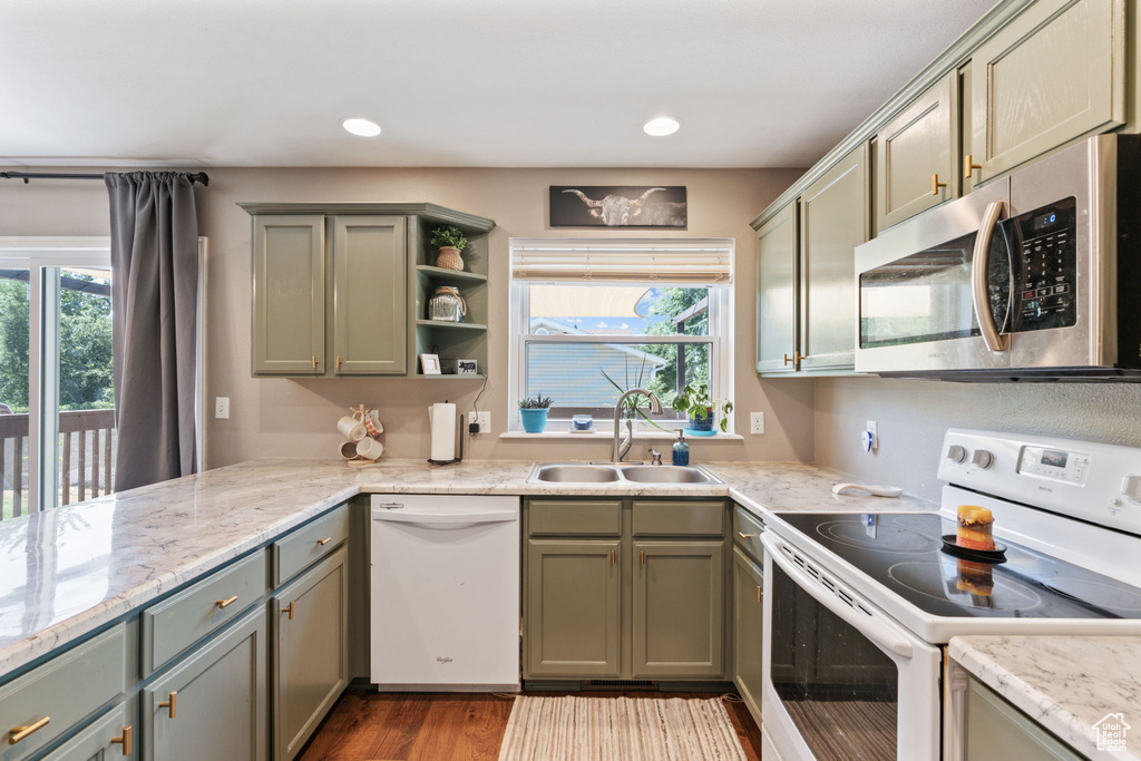 Kitchen featuring wood-type flooring, a healthy amount of sunlight, white appliances, and sink