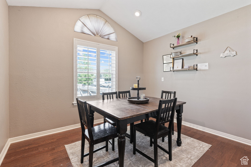 Dining room with dark hardwood / wood-style flooring and lofted ceiling