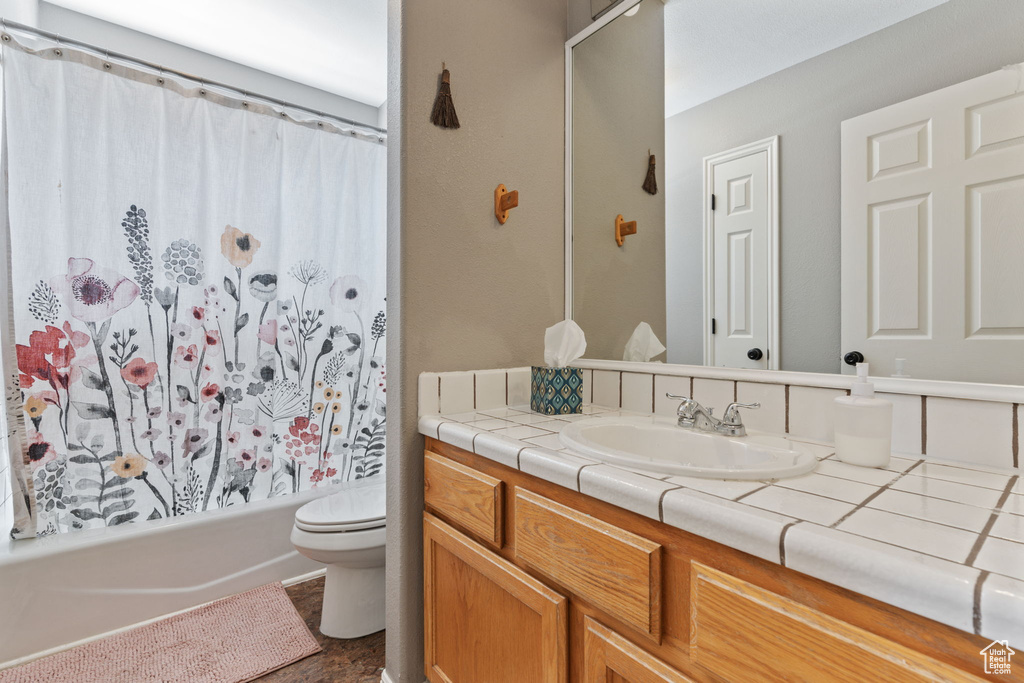 Full bathroom featuring shower / tub combo, tile patterned floors, toilet, and vanity