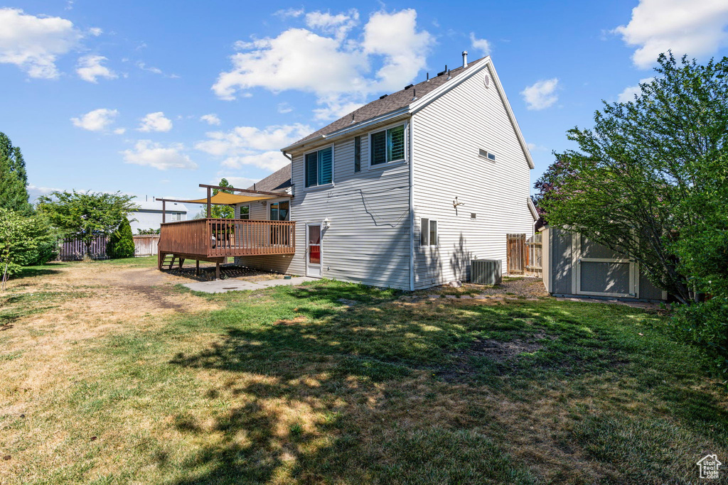 Back of house with central AC, a lawn, and a wooden deck