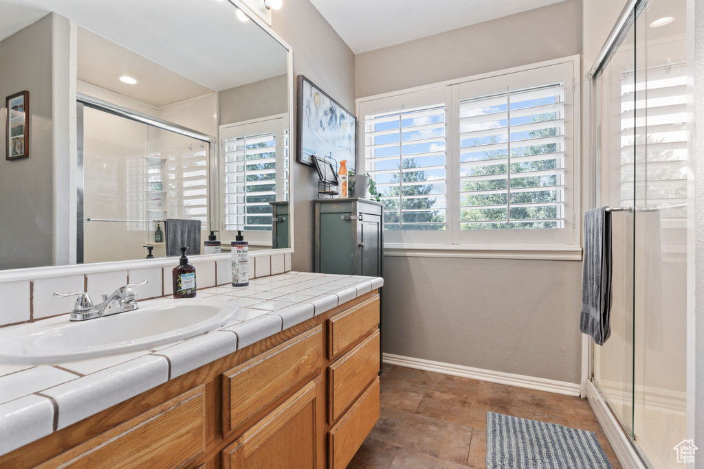 Bathroom featuring a shower with shower door, vanity, and tile patterned floors