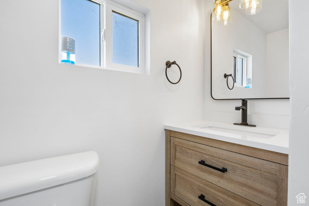 Bathroom with vanity, toilet, and plenty of natural light