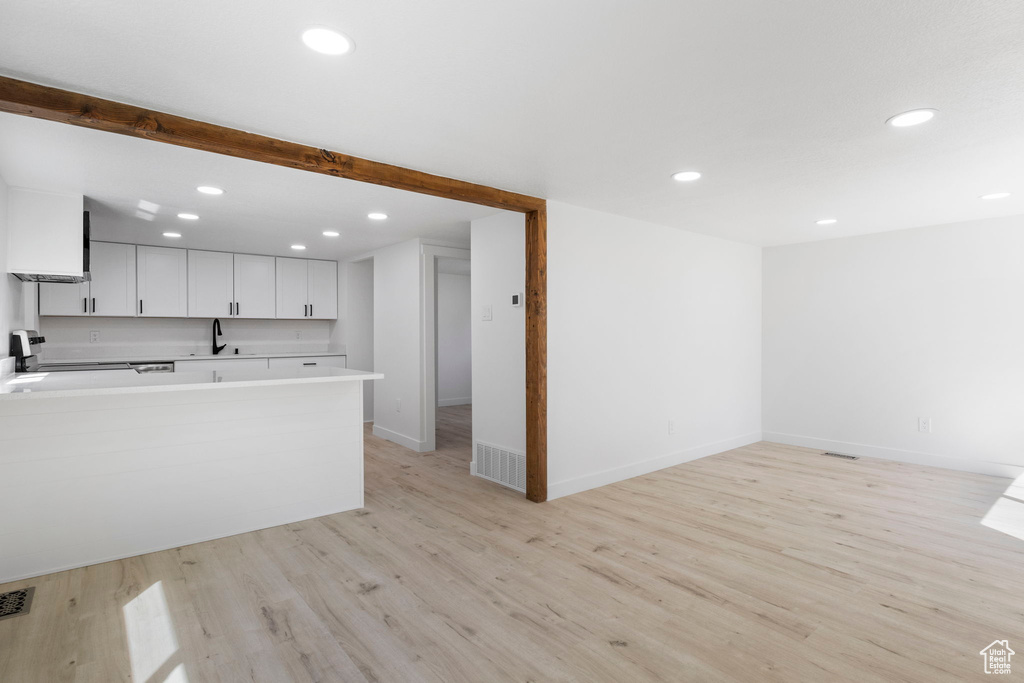 Kitchen with range, sink, white cabinetry, and light hardwood / wood-style flooring