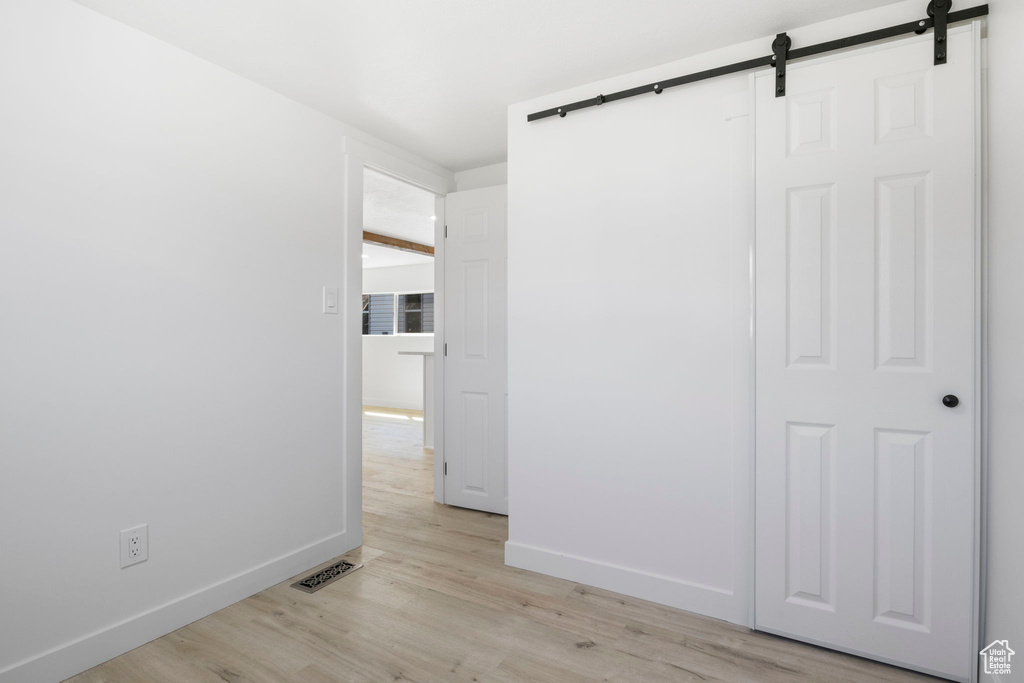 Hallway with light hardwood / wood-style floors and a barn door