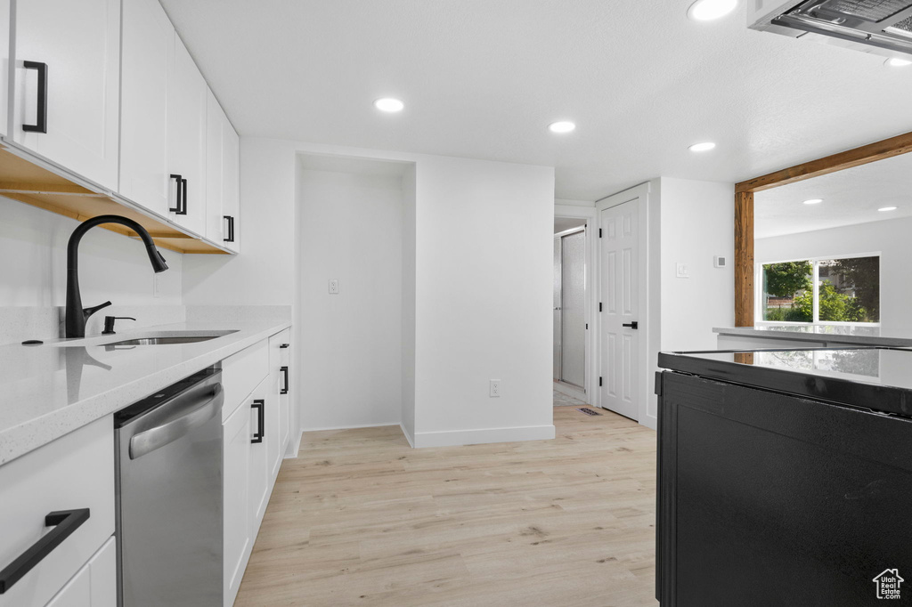 Kitchen featuring white cabinets, dishwasher, light hardwood / wood-style flooring, and sink