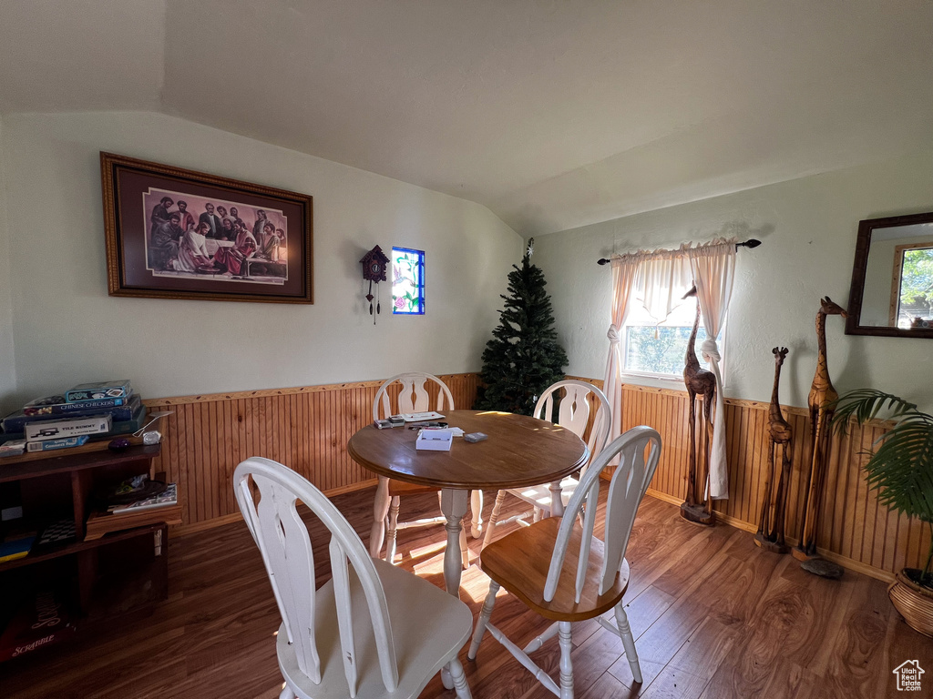 Dining area with hardwood / wood-style floors, a wealth of natural light, and vaulted ceiling