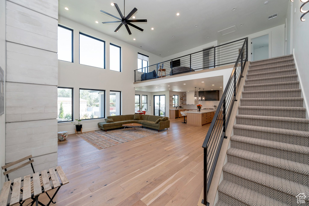 Living room featuring a high ceiling, light wood-type flooring, and ceiling fan